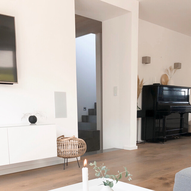 Blick vom Sofa im Wohnzimmer auf das edle schwarze Klavier auf dem milchkaffee-farbenen Lindura Lindura-Holzboden Eiche rustikal milchkaffee im Wohnzimmer